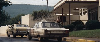 Movie still from “Deliverance” (1972), directed by John Boorman – An old police car parked in front of a hospital; Wide shot, Low angle