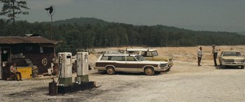 Movie still from “Deliverance” (1972), directed by John Boorman – A couple of cars that are parked in the dirt; Extreme Wide shot, High angle