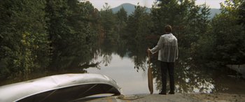 Movie still from “Deliverance” (1972), directed by John Boorman – A man standing next to a boat on a river; Extreme Wide shot, High angle
