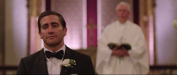 Movie still from “Demolition” (2015), directed by Jean-Marc Vallée – A man in a tuxedo standing in front of a priest holding a bible; Close Up shot, Over the shoulder angle