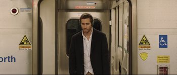 Movie still from “Demolition” (2015), directed by Jean-Marc Vallée – A man in a black jacket and white shirt standing on a train; Medium shot, Over the shoulder angle