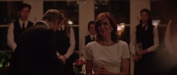 Movie still from “Demolition” (2015), directed by Jean-Marc Vallée – A woman in a white dress standing in front of other people; Medium shot, Over the shoulder angle