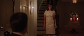 Movie still from “Demolition” (2015), directed by Jean-Marc Vallée – A woman in a white dress standing in front of a staircase; Medium shot, Over the shoulder angle