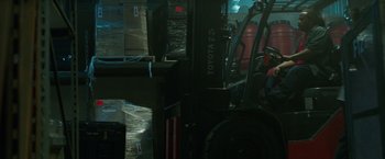 Movie still from “Den of Thieves” (2018), directed by Christian Gudegast – A forklift is parked in a warehouse filled with cardboard boxes; Wide shot, High angle