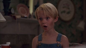 Movie still from “Dennis the Menace” (1993), directed by Nick Castle – A young blonde haired boy wearing overalls and looking surprised; Close Up shot, High angle