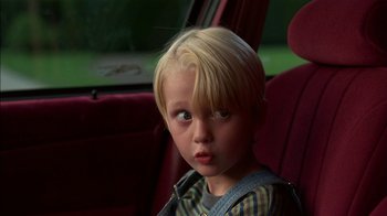 Movie still from “Dennis the Menace” (1993), directed by Nick Castle – A little boy sitting in the back seat of a car; Close Up shot, High angle