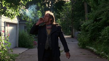Movie still from “Dennis the Menace” (1993), directed by Nick Castle – A man smoking a cigarette while standing on the side of a road; Medium shot, Low angle