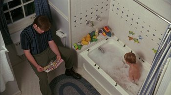 Movie still from “Dennis the Menace” (1993), directed by Nick Castle – A man reading a book to a child in a bath tub; Medium shot, High angle