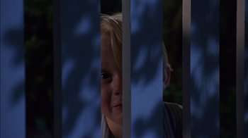 Movie still from “Dennis the Menace” (1993), directed by Nick Castle – A little girl looking through a fence at night; Close Up shot, Low angle