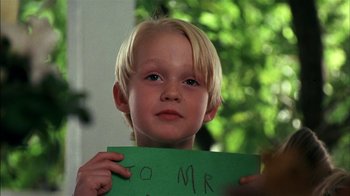 Movie still from “Dennis the Menace” (1993), directed by Nick Castle – A young boy holding up a sign that says " to mr and mrs "; Close Up shot, Low angle