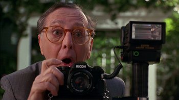 Movie still from “Dennis the Menace” (1993), directed by Nick Castle – An older man holding a camera up to his mouth; Close Up shot, Low angle