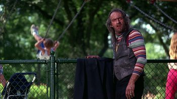 Movie still from “Dennis the Menace” (1993), directed by Nick Castle – An old man standing next to a chain link fence; Medium shot, Low angle