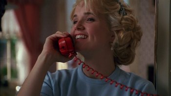 Movie still from “Dennis the Menace” (1993), directed by Nick Castle – A woman talking on a red phone while smiling; Close Up shot, Low angle
