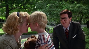 Movie still from “Dennis the Menace” (1993), directed by Nick Castle – A young boy being kissed on the cheek by a woman; Medium shot, Over the shoulder angle