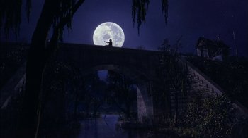Movie still from “Dennis the Menace” (1993), directed by Nick Castle – A person standing on top of a bridge at night with the moon in the background; Extreme Wide shot, Low angle