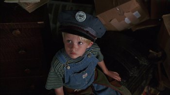 Movie still from “Dennis the Menace” (1993), directed by Nick Castle – A little boy wearing a hat sitting in a room; Close Up shot, High angle