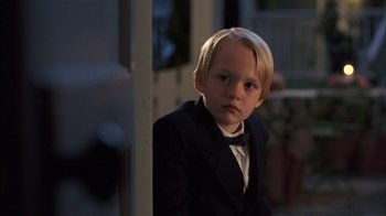Movie still from “Dennis the Menace” (1993), directed by Nick Castle – A young boy in a suit and bow tie; Close Up shot, Over the shoulder angle