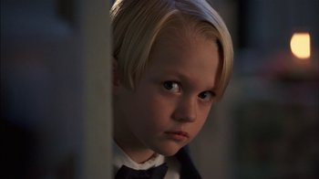 Movie still from “Dennis the Menace” (1993), directed by Nick Castle – A little boy with blonde hair wearing a suit and bow tie; Close Up shot, Low angle