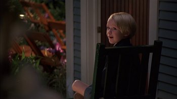 Movie still from “Dennis the Menace” (1993), directed by Nick Castle – A little boy sitting in a chair outside; Medium shot, Over the shoulder angle