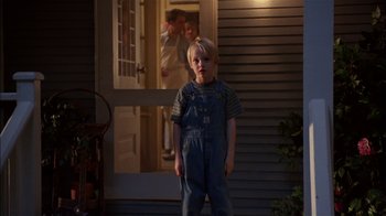 Movie still from “Dennis the Menace” (1993), directed by Nick Castle – A young boy standing in front of a house; Wide shot, Over the shoulder angle