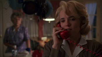 Movie still from “Dennis the Menace” (1993), directed by Nick Castle – A woman talking on a red phone while sitting in a room; Close Up shot, Low angle