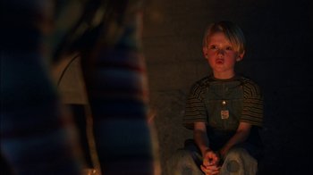 Movie still from “Dennis the Menace” (1993), directed by Nick Castle – A young boy sitting in a dark room; Medium shot, Over the shoulder angle