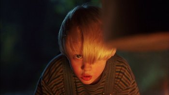 Movie still from “Dennis the Menace” (1993), directed by Nick Castle – A young boy with blonde hair stares into the camera; Close Up shot, Over the shoulder angle