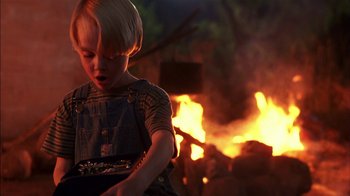 Movie still from “Dennis the Menace” (1993), directed by Nick Castle – A little boy that is standing in front of a fire; Close Up shot, High angle