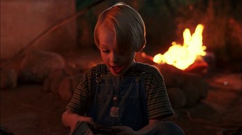 Movie still from “Dennis the Menace” (1993), directed by Nick Castle – A little boy that is sitting in front of a fire; Close Up shot, High angle