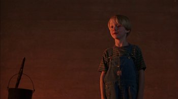 Movie still from “Dennis the Menace” (1993), directed by Nick Castle – A young boy standing in front of an orange wall; Medium shot, Low angle
