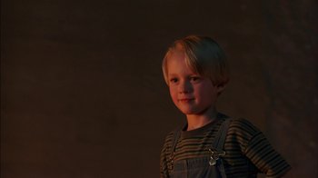 Movie still from “Dennis the Menace” (1993), directed by Nick Castle – A little boy standing in the dark with a smile on his face; Close Up shot, Low angle