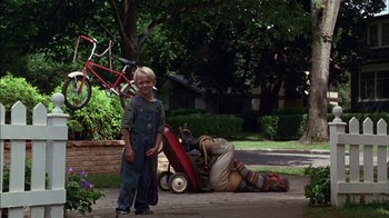 Movie still from “Dennis the Menace” (1993), directed by Nick Castle – A boy standing next to a man laying on the ground; Wide shot, Low angle