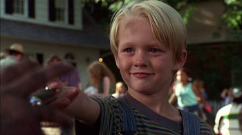 Movie still from “Dennis the Menace” (1993), directed by Nick Castle – A young boy with blonde hair is smiling for the camera; Close Up shot, Low angle