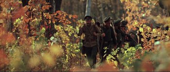 Movie still from “Dersu Uzala” (1975), directed by Akira Kurosawa – A group of men walking through the woods holding guns; Wide shot, High angle
