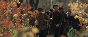 Movie still from “Dersu Uzala” (1975), directed by Akira Kurosawa – A group of men walking through the woods holding guns; Medium shot, Low angle