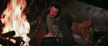 Movie still from “Dersu Uzala” (1975), directed by Akira Kurosawa – A man sitting on the ground writing on a piece of paper; Medium shot, High angle