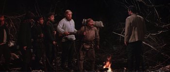 Movie still from “Dersu Uzala” (1975), directed by Akira Kurosawa – A group of people standing around a fire; Wide shot, Low angle