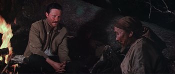 Movie still from “Dersu Uzala” (1975), directed by Akira Kurosawa – Two men sitting on the ground talking to each other; Medium shot, High angle