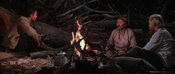 Movie still from “Dersu Uzala” (1975), directed by Akira Kurosawa – A man sitting in front of a fire in the woods; Medium shot, High angle