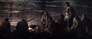 Movie still from “Dersu Uzala” (1975), directed by Akira Kurosawa – A group of people sitting around a fire pit; Wide shot, High angle