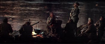 Movie still from “Dersu Uzala” (1975), directed by Akira Kurosawa – A group of people gathered around a fire; Wide shot, Low angle