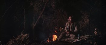 Movie still from “Dersu Uzala” (1975), directed by Akira Kurosawa – A man sitting in front of a fire in the dark; Wide shot, High angle