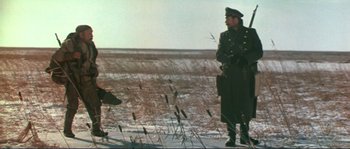 Movie still from “Dersu Uzala” (1975), directed by Akira Kurosawa – A man and a dog standing in a field; Wide shot, Low angle
