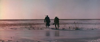 Movie still from “Dersu Uzala” (1975), directed by Akira Kurosawa – Two people are walking on the shore of a frozen lake; Wide shot, Low angle