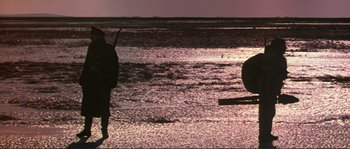 Movie still from “Dersu Uzala” (1975), directed by Akira Kurosawa – A man standing on a beach near a body of water; Extreme Wide shot, Low angle