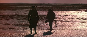 Movie still from “Dersu Uzala” (1975), directed by Akira Kurosawa – Two men in military uniforms walking across a beach; Wide shot, Low angle