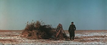 Movie still from “Dersu Uzala” (1975), directed by Akira Kurosawa – A man standing next to a pile of grass; Wide shot, Low angle