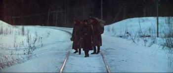 Movie still from “Dersu Uzala” (1975), directed by Akira Kurosawa – A group of people walking across a snow covered road; Wide shot, High angle