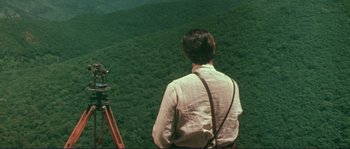 Movie still from “Dersu Uzala” (1975), directed by Akira Kurosawa – A man looking out over a lush green hillside; Extreme Wide shot, High angle