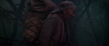 Movie still from “Dersu Uzala” (1975), directed by Akira Kurosawa – An old man wearing a head scarf and carrying a large bag on his back; Medium shot, Low angle
